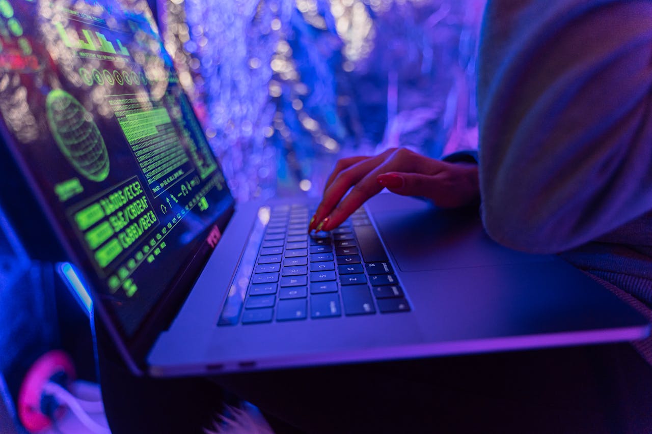 Crafting Captivating Headlines: Your awesome post title goes here Close-up of hands typing on a laptop displaying cybersecurity graphics, illuminated by purple light.